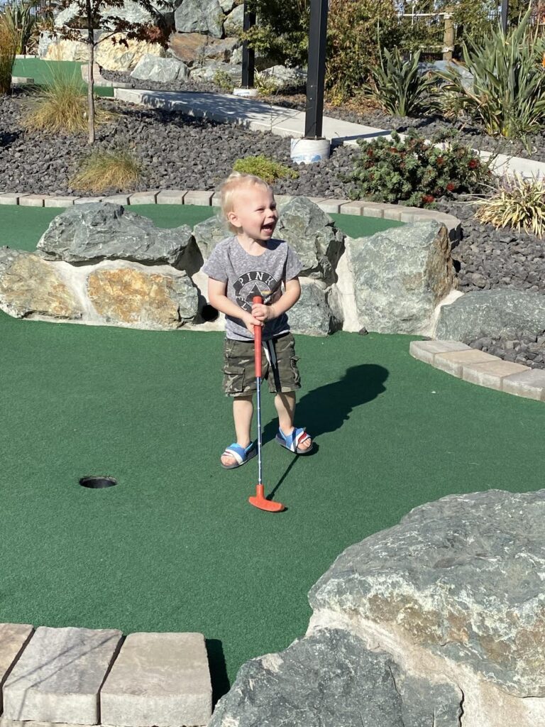 little boy playing mini golf