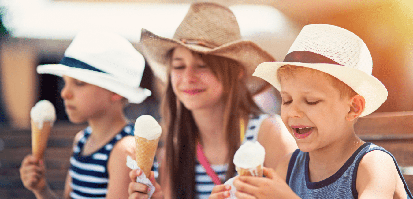 three kids with hats on eating vanilla ice cream cones